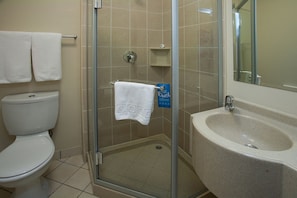 Un baño con cabina de ducha de vidrio, inodoro y lavamanos.