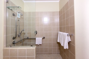 Un área de ducha con puerta de cristal, un pasamanos y un perchero para toallas.