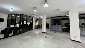 A spacious lobby with a reception desk, a kitchenette, and a seating area. - Junction Hostels (Makati)