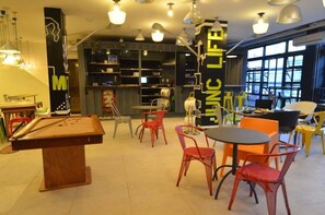 Une pi èce avec une table de billard, des chaises rouges, une petite table et une grande fenêtre.