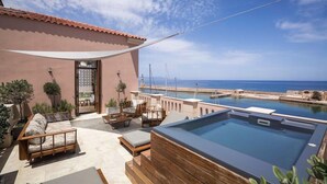 A rooftop terrace with a hot tub, seating area, and a view of the sea.