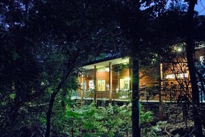 A wooden cabin with a balcony, surrounded by dense foliage. - Monteverde Luxury Hotel (Monteverde)
