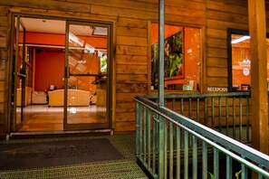 A hotel entrance with a reception desk, a glass door leading to a lobby, and a staircase. - Monteverde Luxury Hotel (Monteverde)