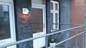A building with a dark facade, white-framed windows, and a metal railing. - Herning City Apartments (Herning)
