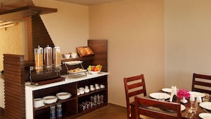 A breakfast buffet setup with a coffee station, fruit, and bread. - At Home B&B Dona Paula (Panaji)