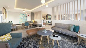 A modern hotel lobby with sofas, round tables, and a decorative wall. - TownePlace Suites by Marriott Painesville Mentor (Mentor)