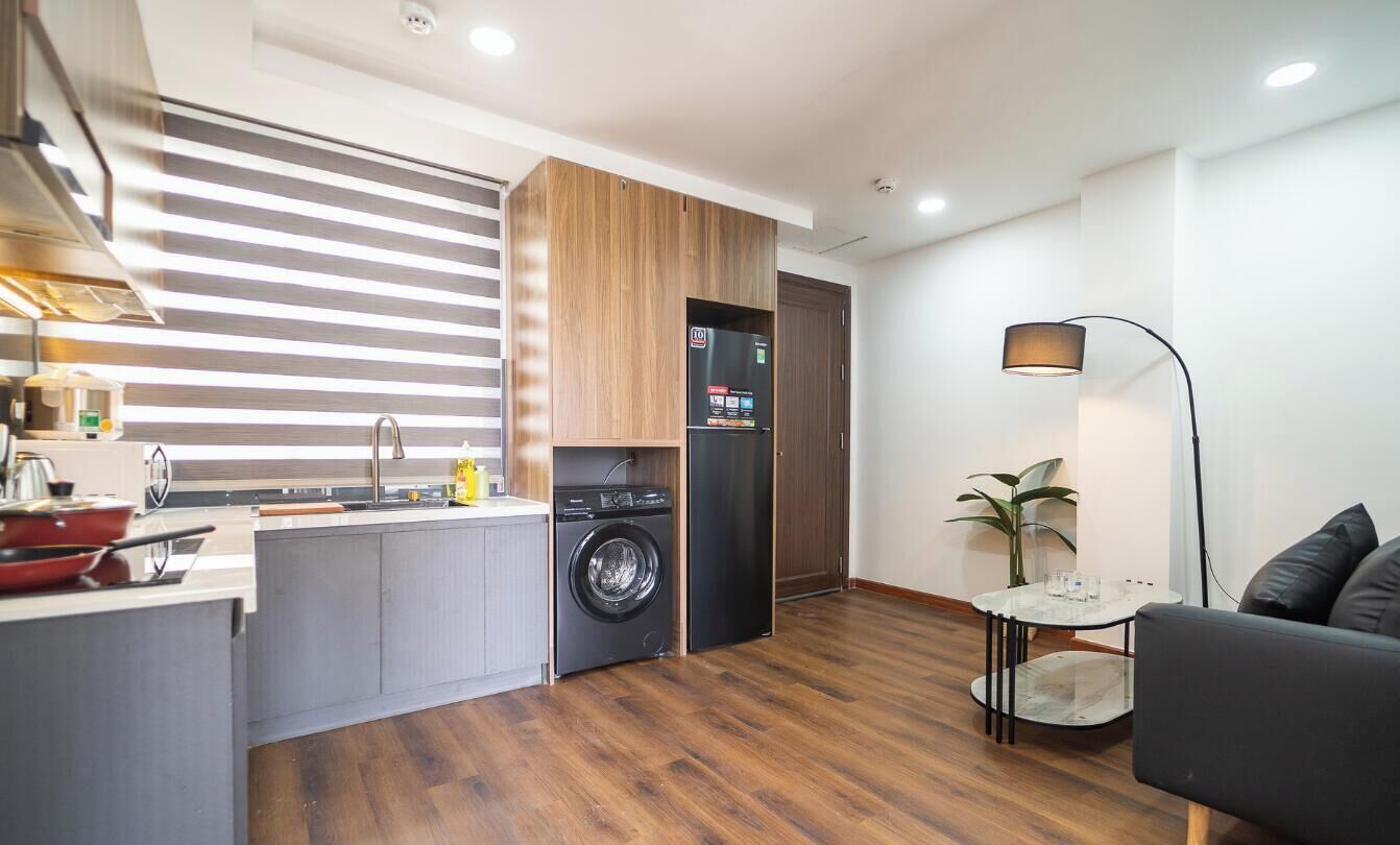 Una cocina compacta con lavadora, un comedor con mesa y sillas, y un sofá.