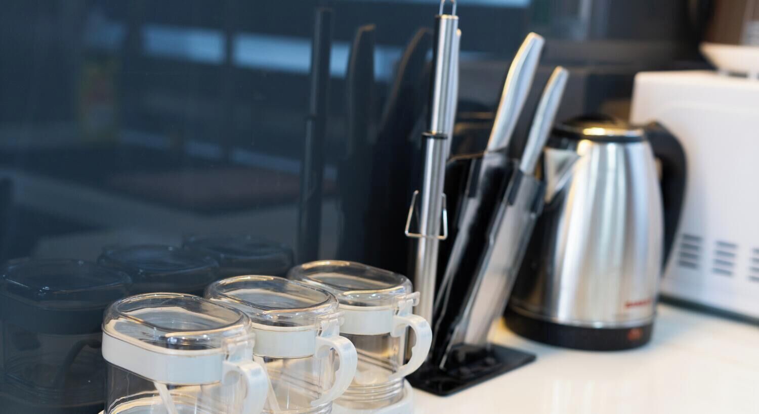 A kitchen counter with a coffee maker, a knife block, and a mug with a lid.