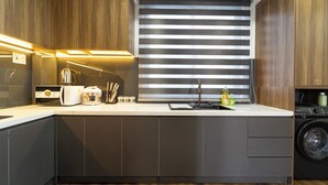 Une cuisine moderne équipée d’un lave-linge intégré, d’une machine à café et d’une bouilloire.