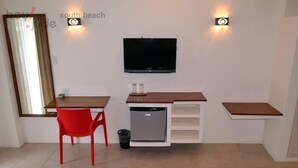 Eine kompakte Küchenzeile mit Fernseher, einem roten Sessel und einem kleinen Kühlschrank.