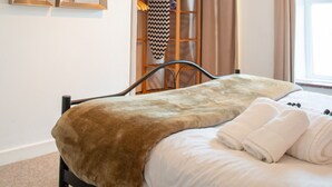 Ein Schlafzimmer mit Bett, großem Spiegel, Fenster mit Vorhängen und einer Deckenleuchte.
