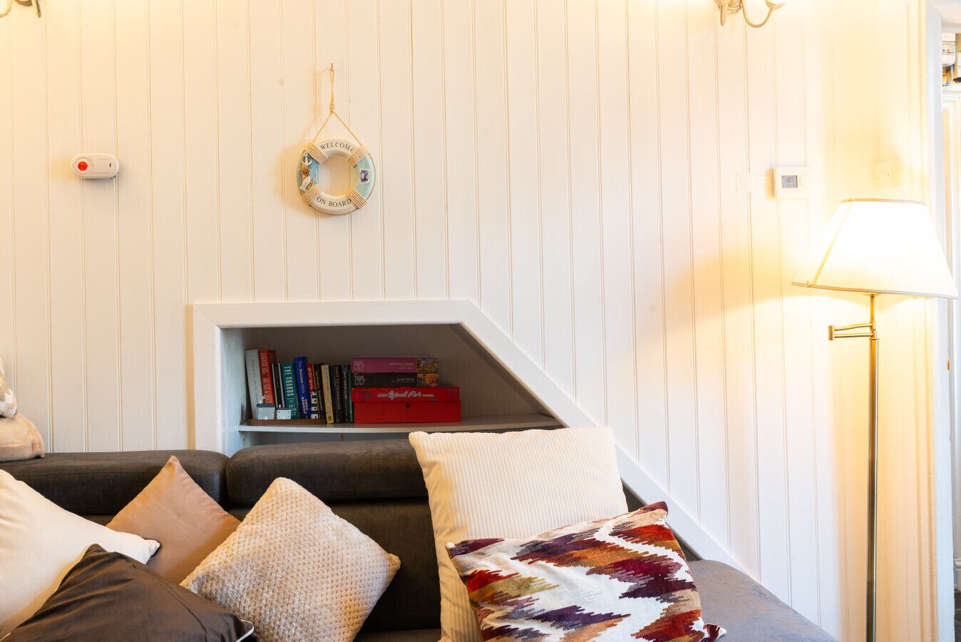 Un salon chaleureux avec une bibliothèque intégrée, une lampe et un panneau décoratif accueillant.