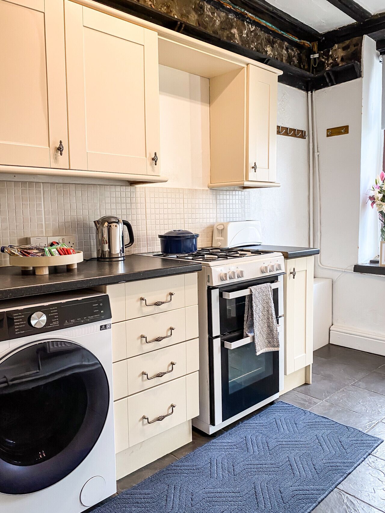 Een kleine keuken met een wasmachine, een fornuis en een spoelbak.