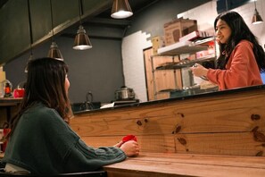 A person sitting at a wooden counter in a cafe, holding a red cup. - Duckstay Hostel (Taipei)