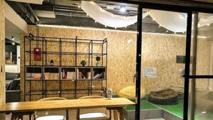 A room with a wooden table, chairs, a bookshelf, and a bed with a green mattress. - Duckstay Hostel (Taipei)