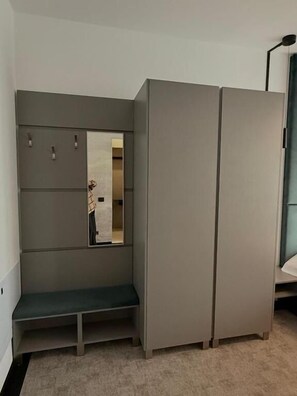 Une pièce avec une armoire grise, un banc et un miroir.