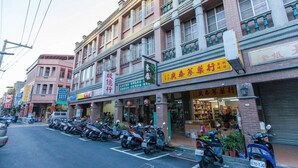 A street with multiple shops and a row of parked scooters. - 9ine Hotel (Taipei)