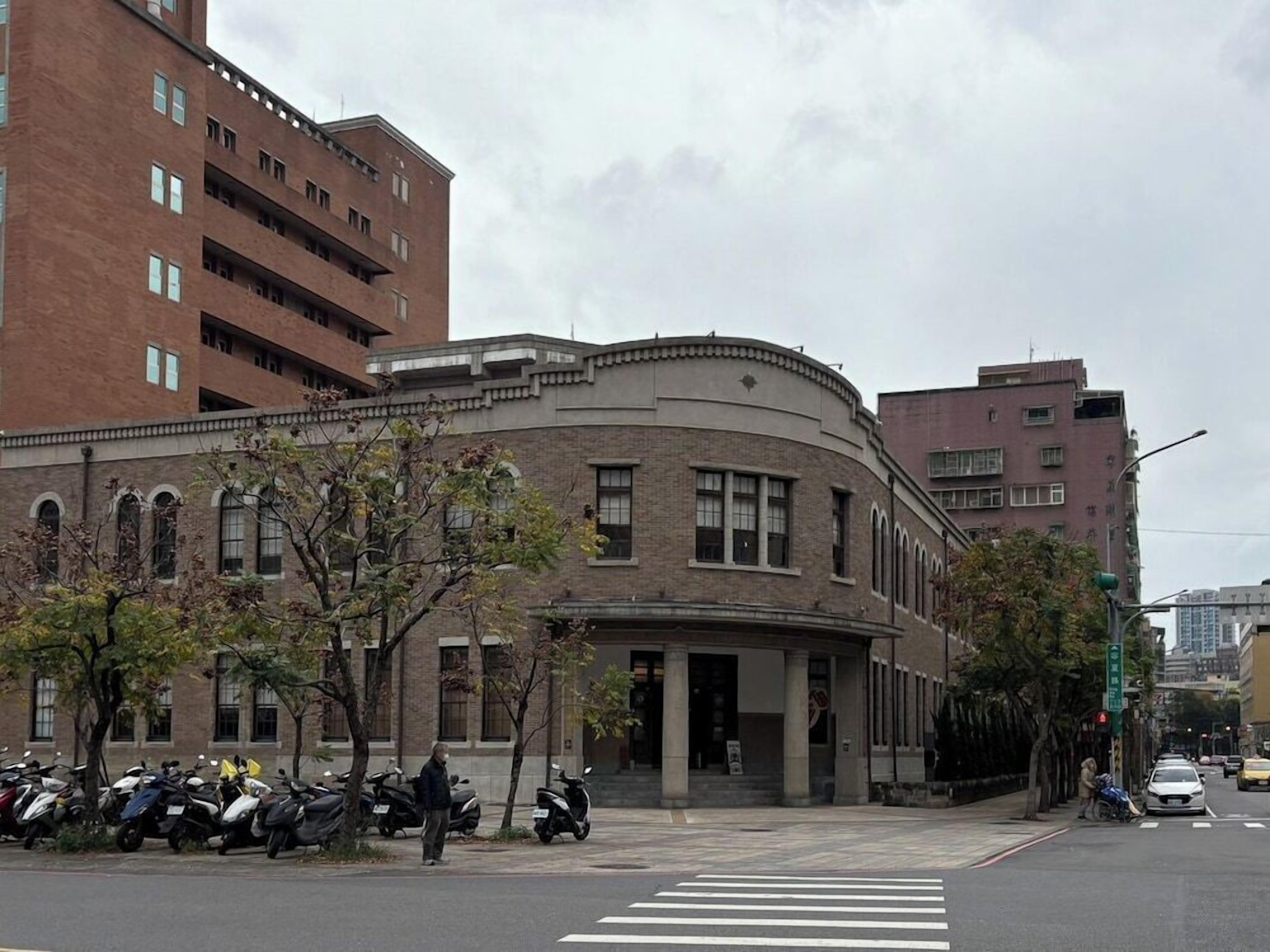 A multi-story building with a curved facade, large windows, and a central entrance.