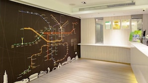 A modern hotel lobby with a large map mural on the wall, a reception desk, and a wooden floor. - 9ine Hotel (Taipei)