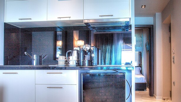 A modern kitchen with stainless steel appliances, a marble countertop, and a view into the adjacent bedroom. - Art Hotel (Kassandra)