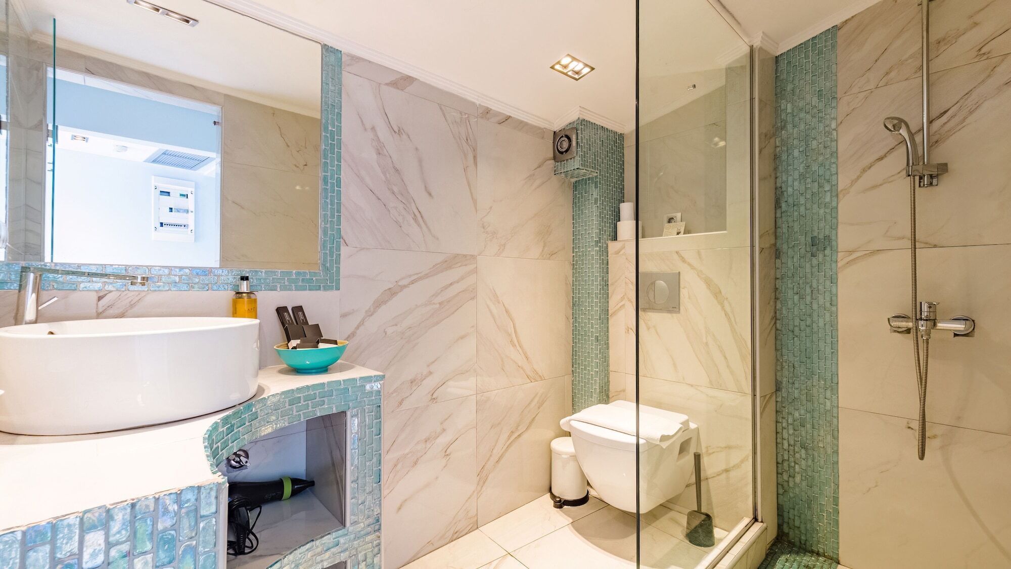 A bathroom with a marble sink, a glass shower enclosure, and a toilet.