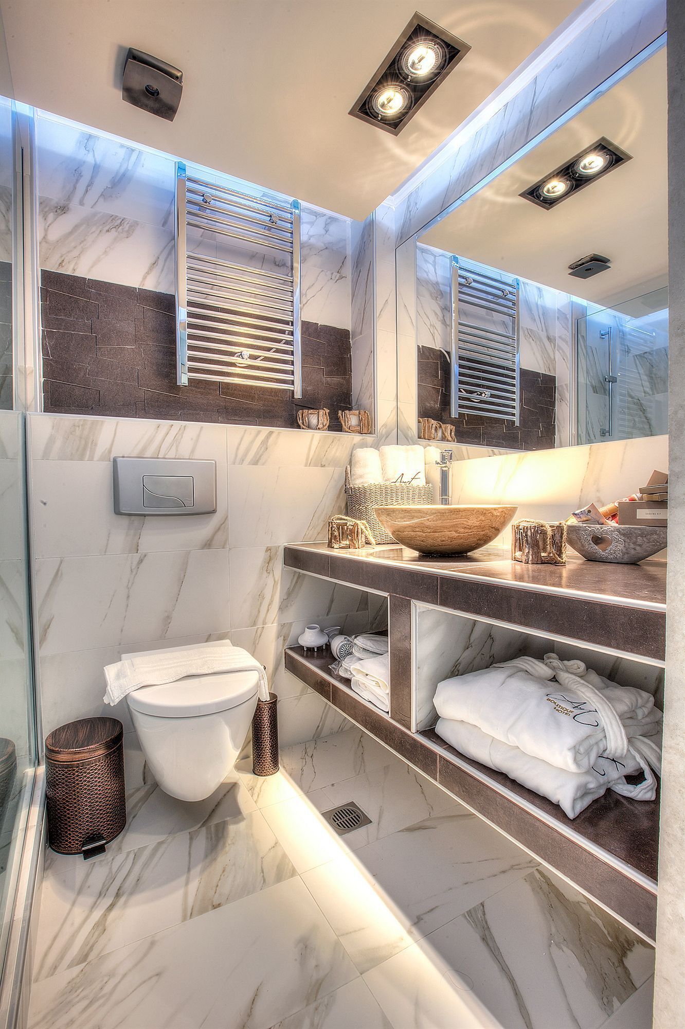 A modern bathroom with a marble floor, a large mirror, a vessel sink, and a toilet.