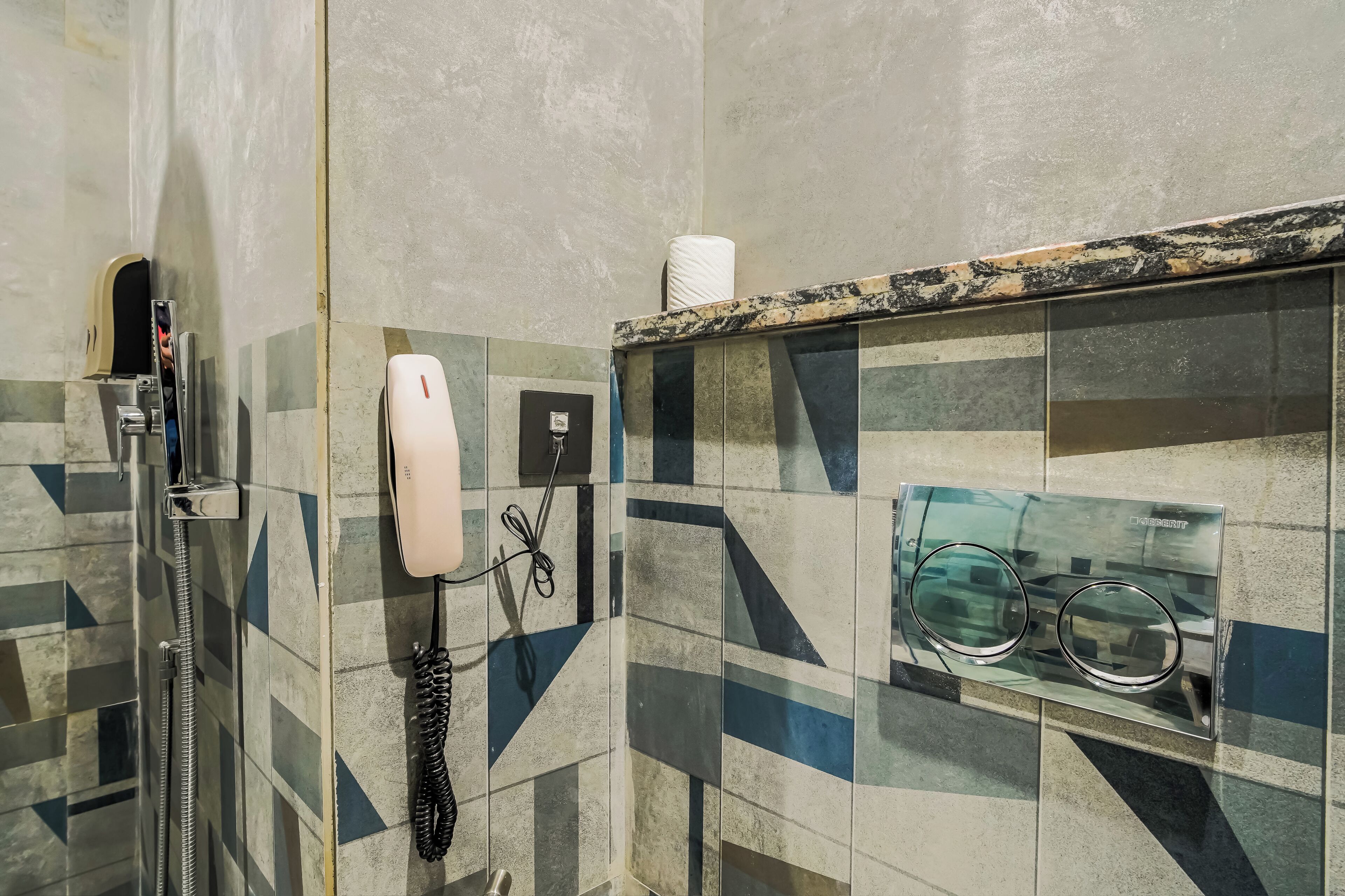 Une salle de bain dotée d’une douche à parois en verre, d’un téléphone et d’un distributeur de serviettes.