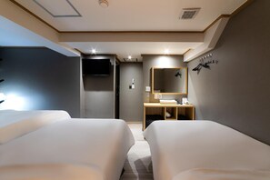 Habitación de hotel con dos camas, un escritorio con espejo y televisión.