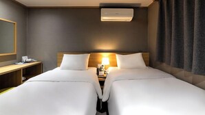 A hotel room with two beds, a desk, a lamp, and an air conditioning unit. - Hotel Stay Inn Seoul Station (Seoul)