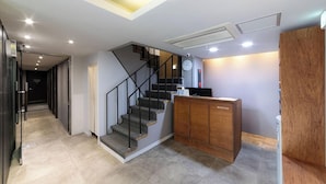 A modern interior with a staircase, a reception desk, and a hallway leading to another room. - Hotel Stay Inn Seoul Station (Seoul)