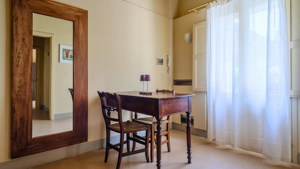 A room with a wooden desk, two chairs, a mirror, and a window with sheer curtains. - Masseria Bernardini (Nardò)