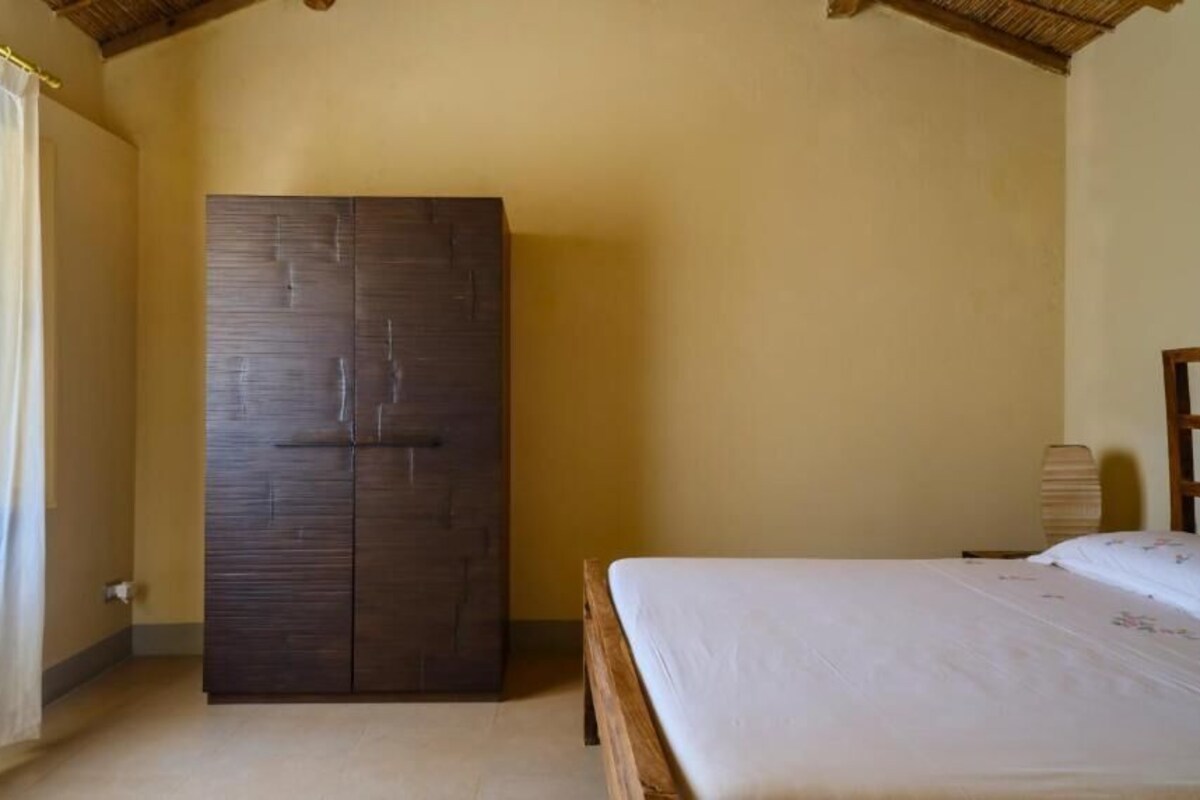 A bedroom with a bed, a wardrobe, and a window with curtains.
