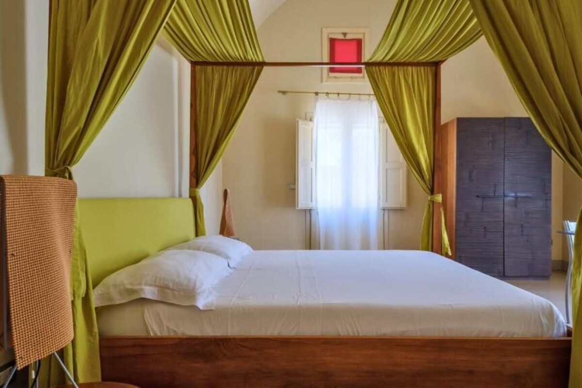 A single bed with green curtains, a wooden headboard, and a white mattress.