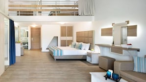 Une chambre d’hôtel moderne avec un lit en mezzanine, un coin salon avec un canapé, une petite table et une salle de bain visible au fond.
