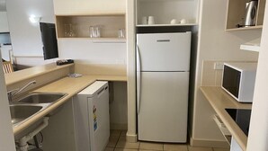 Una cocina compacta con refrigerador, microondas y pileta.