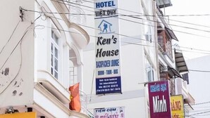 A building with multiple signs advertising various businesses including a hotel, a guest house, and a hairdressing salon. - Ken Apos S House Backpackers Downtown (Da Lat)