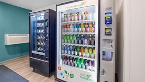 Two HelloGoodness vending machines in a room with teal walls and a wooden floor.