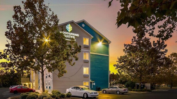 A hotel with a sign reading "Woodspring Suites."