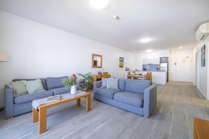 Een moderne woonkamer met twee banken, een salontafel en een keuken op de achtergrond.