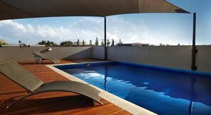 A rooftop swimming pool with a clear view of the city skyline, a lounge chair, and a pergola providing shade. - Mainstay Suites Mackay (Mackay)