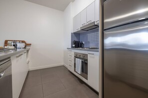 A modern kitchen with stainless steel appliances, a coffee maker, and a tray with breakfast items. - Mainstay Suites Mackay (Mackay)