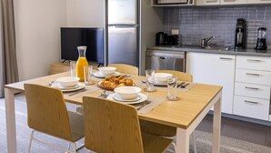 A modern kitchen with a dining area, equipped with a refrigerator, microwave, coffee maker, and dishwasher. - Mainstay Suites Mackay (Mackay)