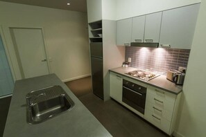 A modern kitchen with a stainless steel sink, a built-in oven, and a countertop with a toaster. - Mainstay Suites Mackay (Mackay)