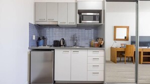 A compact kitchen with white cabinets, a microwave, and a small refrigerator. - Mainstay Suites Mackay (Mackay)
