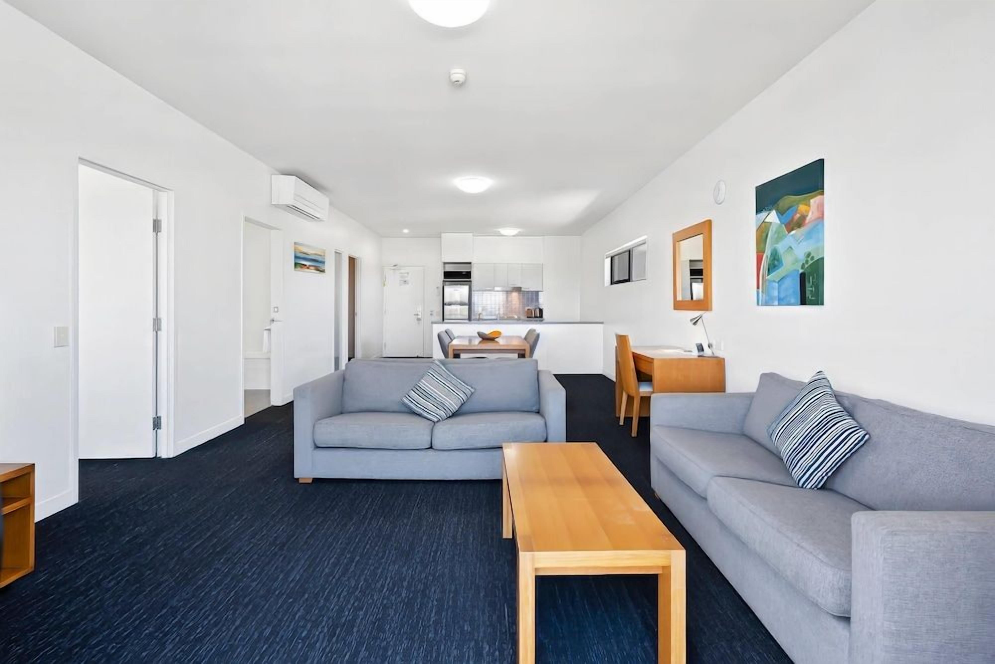 A modern living room with a sofa, a coffee table, and a dining area with a table and chairs.
