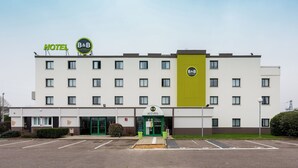 A hotel with a green entrance, multiple windows, and a parking lot. - B&B Hotel Rouen St Etienne Du Rouvray (Saint-Etienne-du-Rouvray)