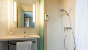 A bathroom with a sink, mirror, and shower. - B&B Hotel Rouen St Etienne Du Rouvray (Saint-Etienne-du-Rouvray)