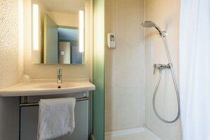 A bathroom with a sink, mirror, and shower. - B&B Hotel Rouen St Etienne Du Rouvray (Saint-Etienne-du-Rouvray)