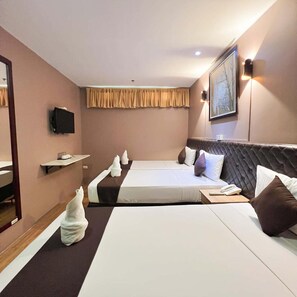 A hotel room with two beds, a flat-screen TV, a bedside table, a mirror, and a painting on the wall. - Cebu Capitol Central Hotel and Suites Powered by Cocotel (Cebu City)