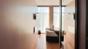 Ein modernes Hotelzimmer mit einem großen Spiegel, einem Bett, einem kleinen Tisch und einem Fenster mit Vorhängen.